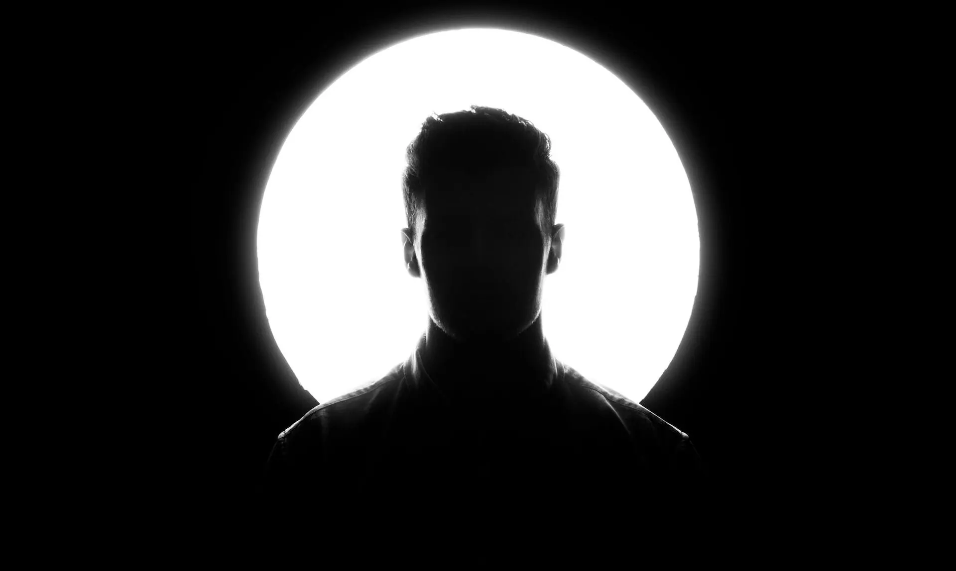 Siluetă de om în fața unui cerc de lumină albă