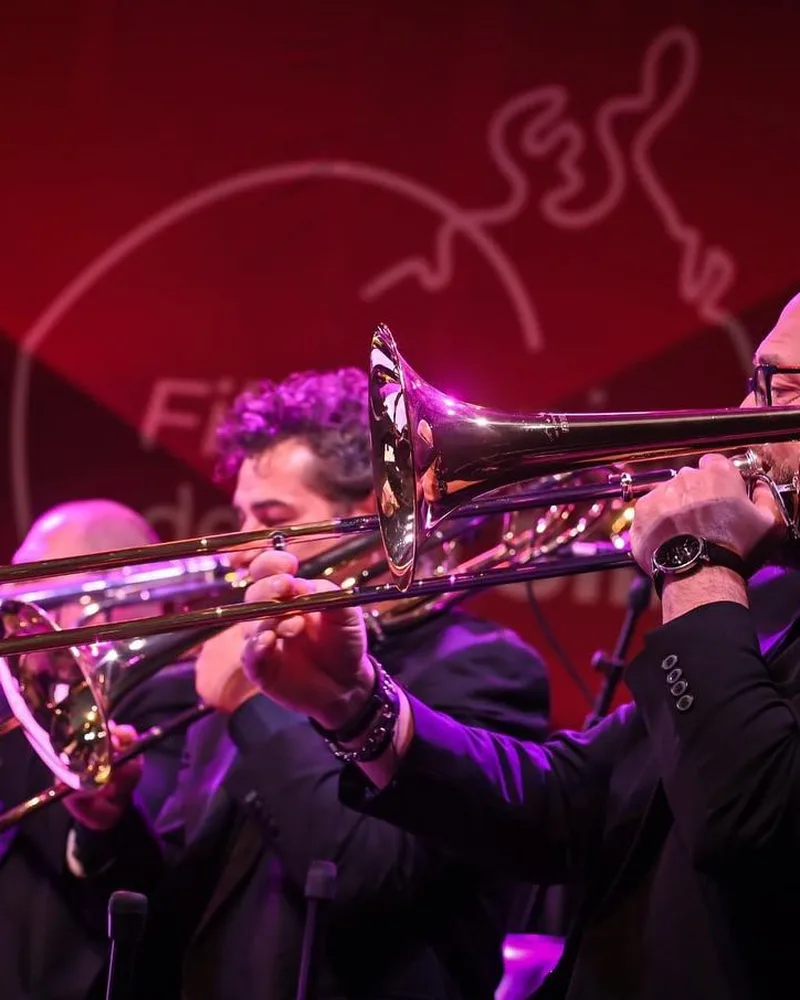 Bucharest Jazz Orchestra pe scenă, într-o sală în lumină roșie