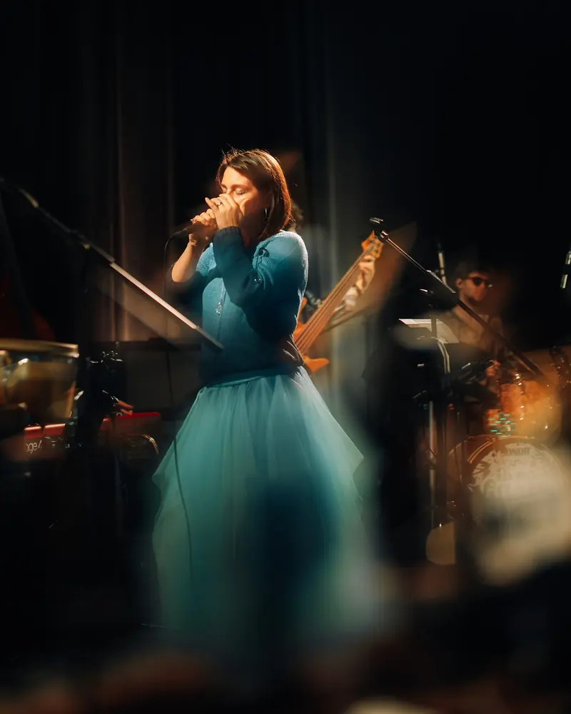 Luiza Zan cântând pe scenă, în rochie turcoaz