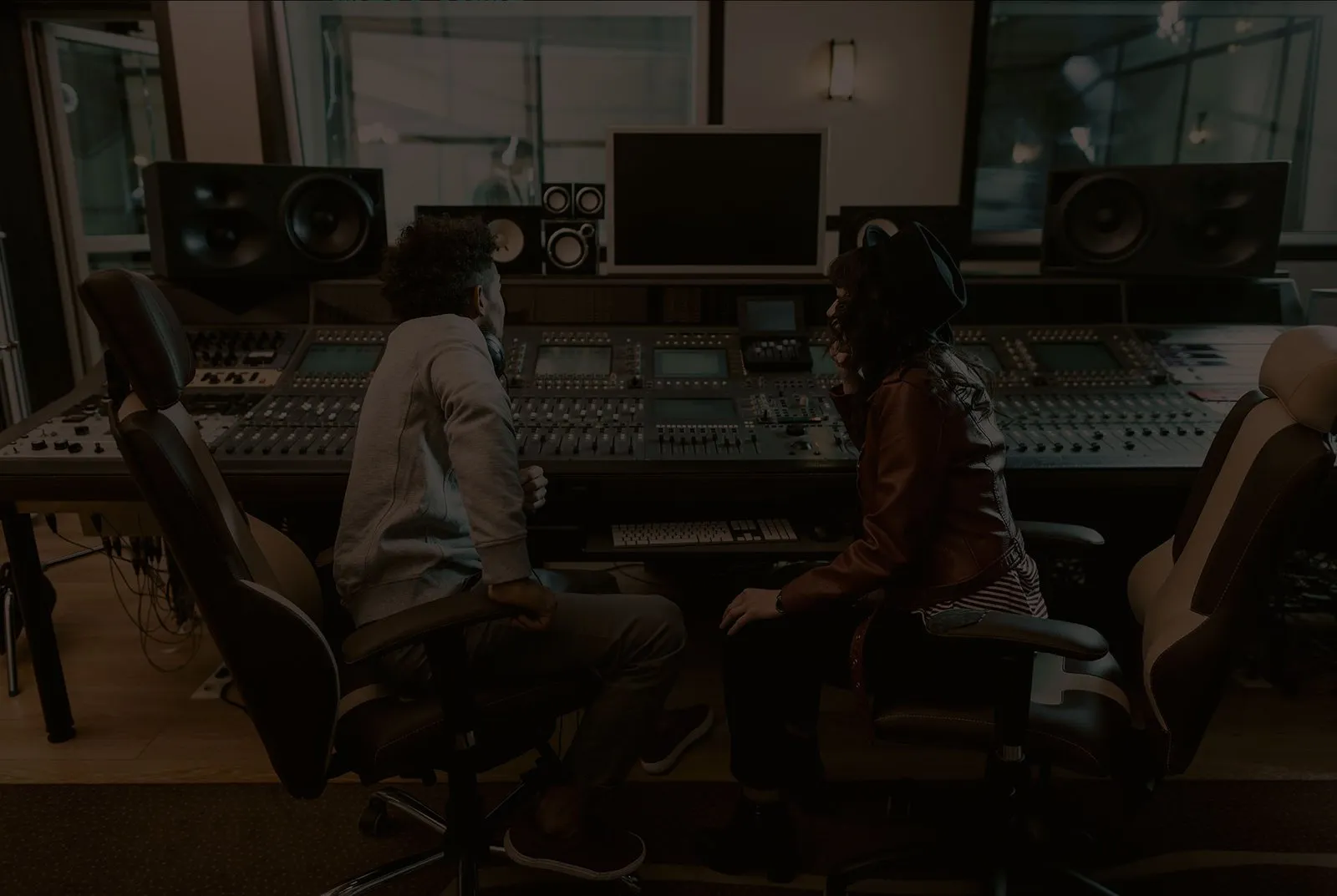 Doi oameni la o consolă de mixaj, într-un studio de înregistrări